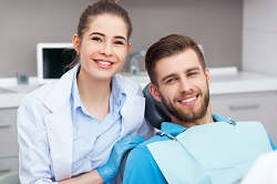 female dental hygienist smiling next to male patient in dental chair, general dentistry Warren, OH